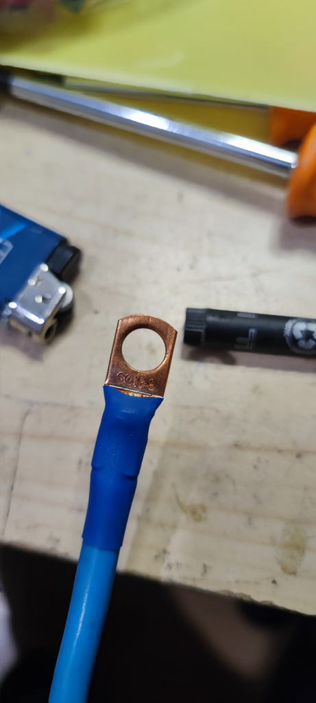 The wire is clamped and then soldered to a copper ring terminal. After that, a heat-shrink tube is applied.